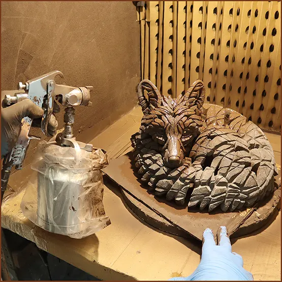 Picture of a finished Fox sculpture casting being spray painted with an undercoat.