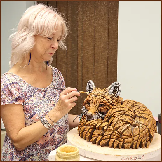 Carole Appleby our Head Studio Painter applying paint by hand to a Fox sculpture