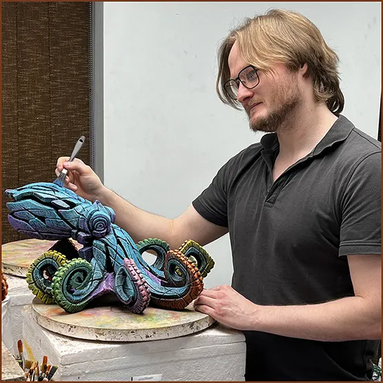Dylan our Assistant Studio Painter applying paint by hand to an Octopus sculpture