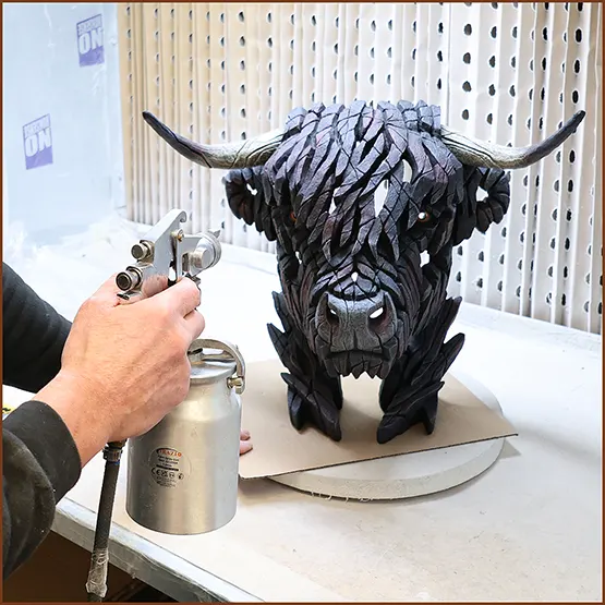 Picture of a finishing lacquer being sprayed onto a black painted Highland cow sculpture