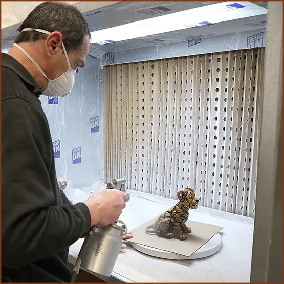 Kevin spraying a finishing lacquer to a painted Tiger Cub sculpture